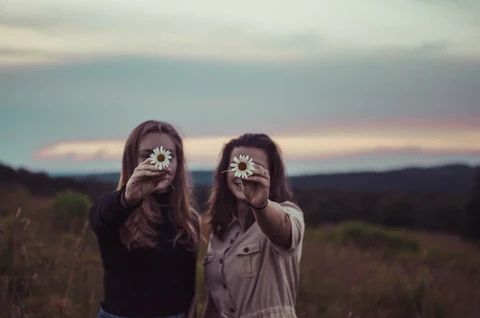 Two girls holding up a flower